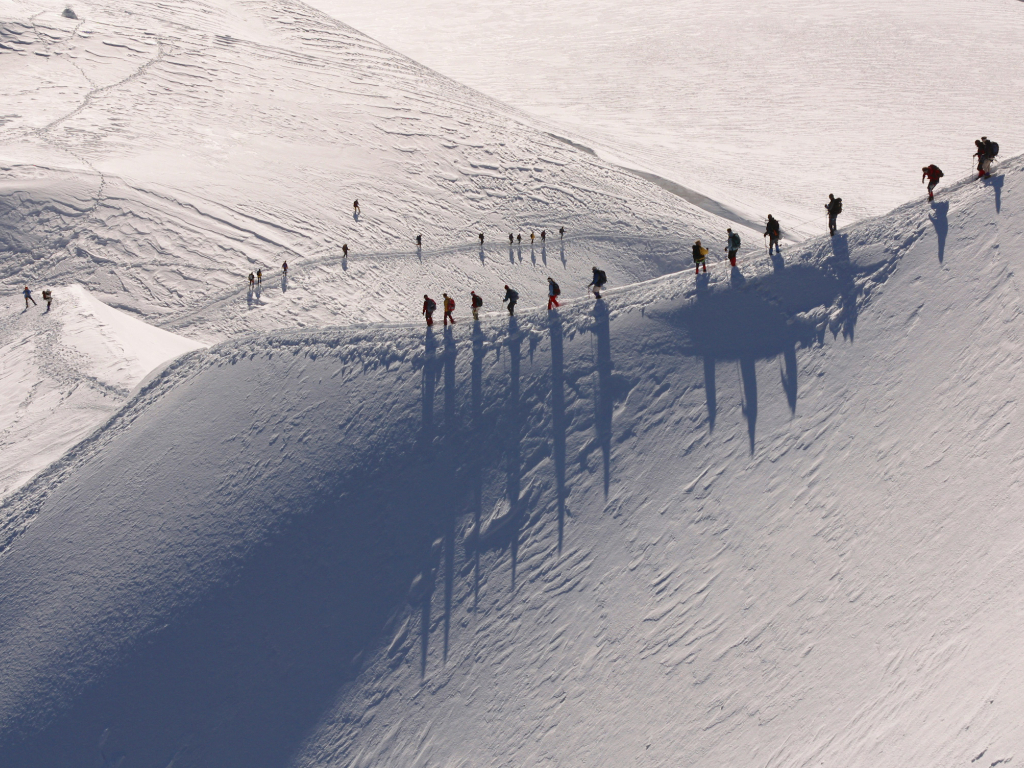 Gruppe besteigt verschneiten Berg.