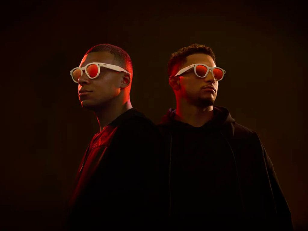Von links: Fußball-WM-Sieger und Oakley-Athlet Kylian Mbappé und Super Bowl-Star und Oakley-Athlet Patrick Mahomes tragen eine weiße Brillenfassung der neuen Oakley Meta HSTN-Brille mit orangenen Prizm-Gläsern